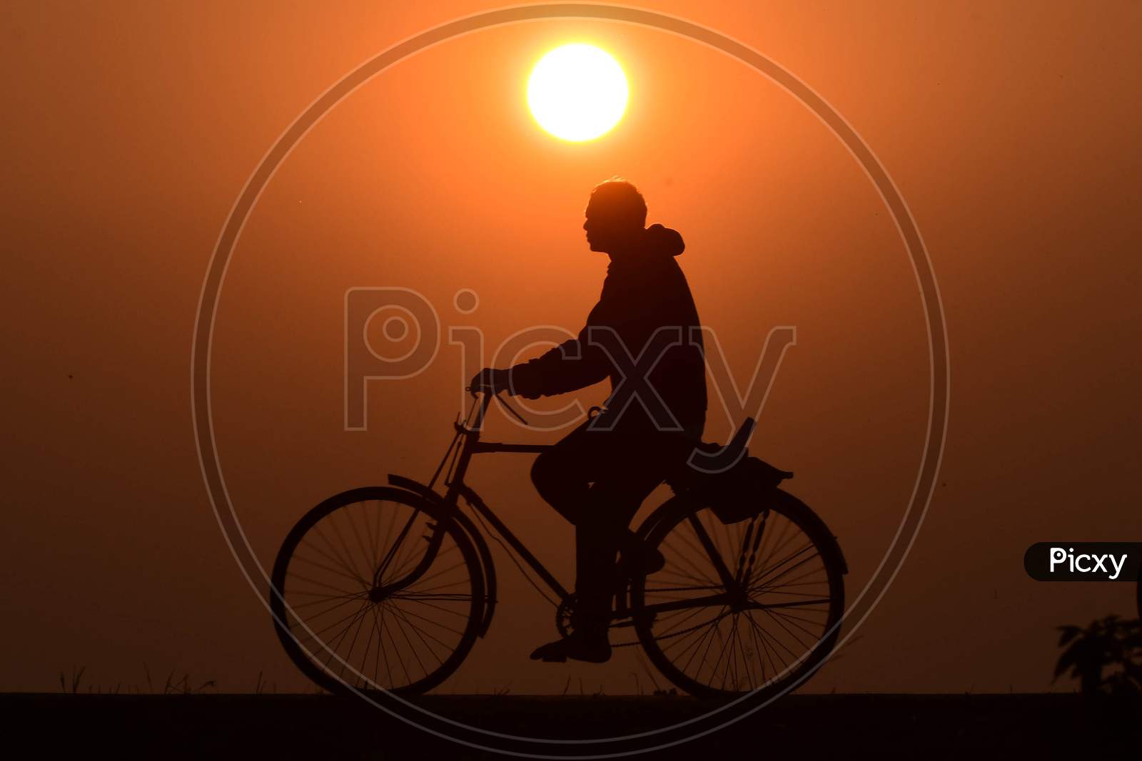 A man rides a bicycle during  the last sunset of the year in  Assam on Dec 31,2020