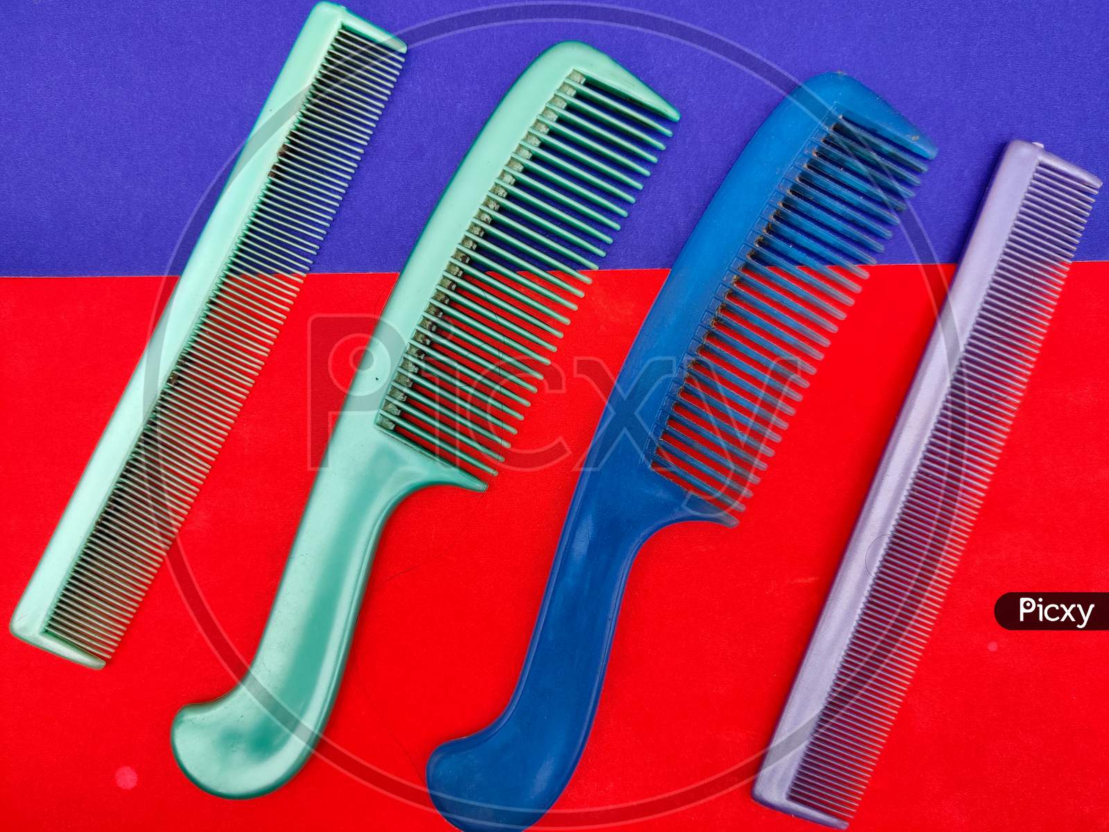 4 Colorful Used Combs Isolated On Red And Blue Background