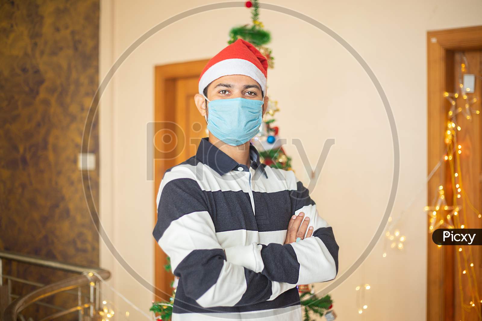 Portrait Of Young Man Wearing Mask And Santa Hat Standing Cross Arm, Christmas Celebration Holiday Concept, Covid-19 Pandemic.