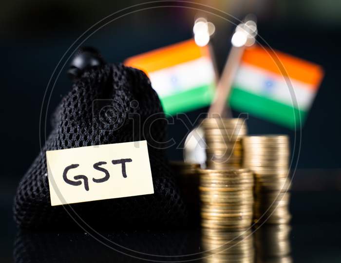 Bag With Gst Sticker In Front Of The Stack Of Coins And Indian Flag As Background - Concept Goods And Service Indirect Tax Collection In India