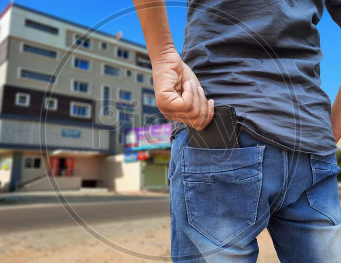 Young Indian Man Pulling Out Wallet From Back Pocket In Market