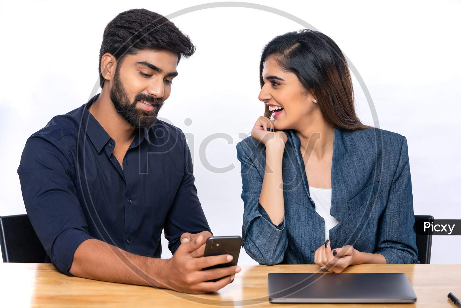 Indian working colleagues discussing and gesturing wile browsing on a mobile