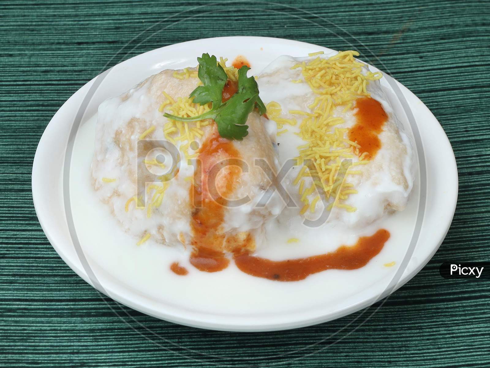 Dahi Vada Or Bhalla Is A Popular Snack In India. It Is Prepared By Soaking Vadas In Thick Dahi / Curd. Garnished With Coriander Leaves, Grated Carrots And Kara Boondi With Tamarind Chutney, Selective Focus