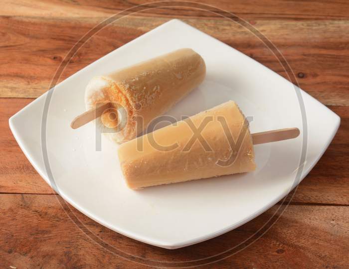 Malai Kulfi Served In White Plate Over A Rustic Wooden Background, Selective Focus