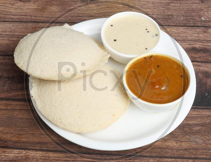Idli Or Idly Is A Healthy Indian, Vegetarian, Traditional And Popular Steam Cooked Rice Cakes Served With Bowls Of Chutney And Sambar As Side Dishes.Selective Focus