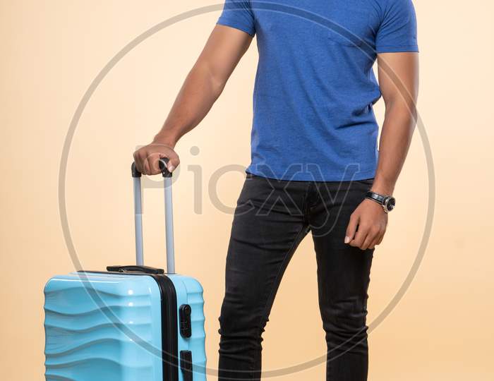 Indian smiling young traveler with a trolley bag