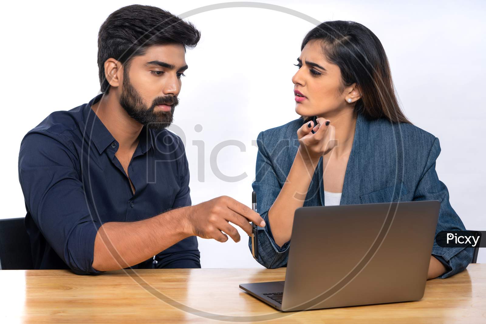 Indian office colleagues smiling while discussing work with a laptop