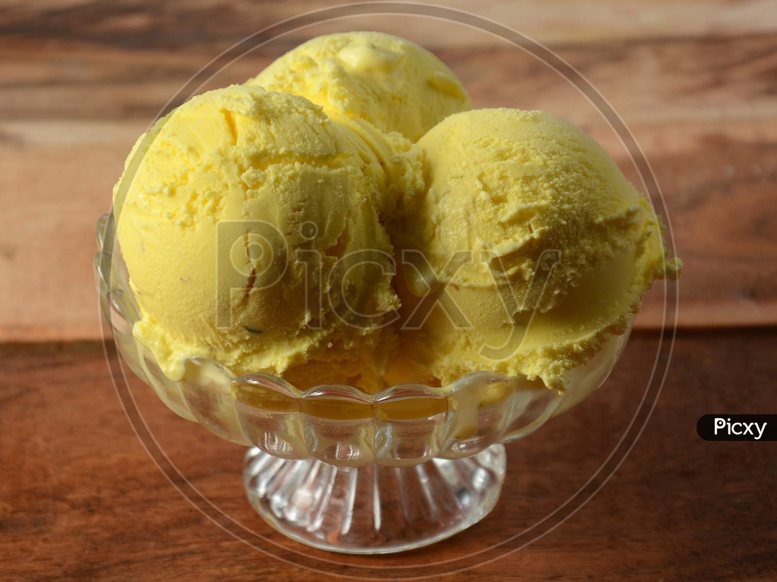 Kesar Pista Ice Cream Scoops Served In A Glass Bowl Over A Rustic Wooden Table, Selective Focus