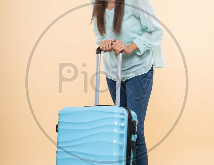 Indian smiling young woman traveler with a trolley bag
