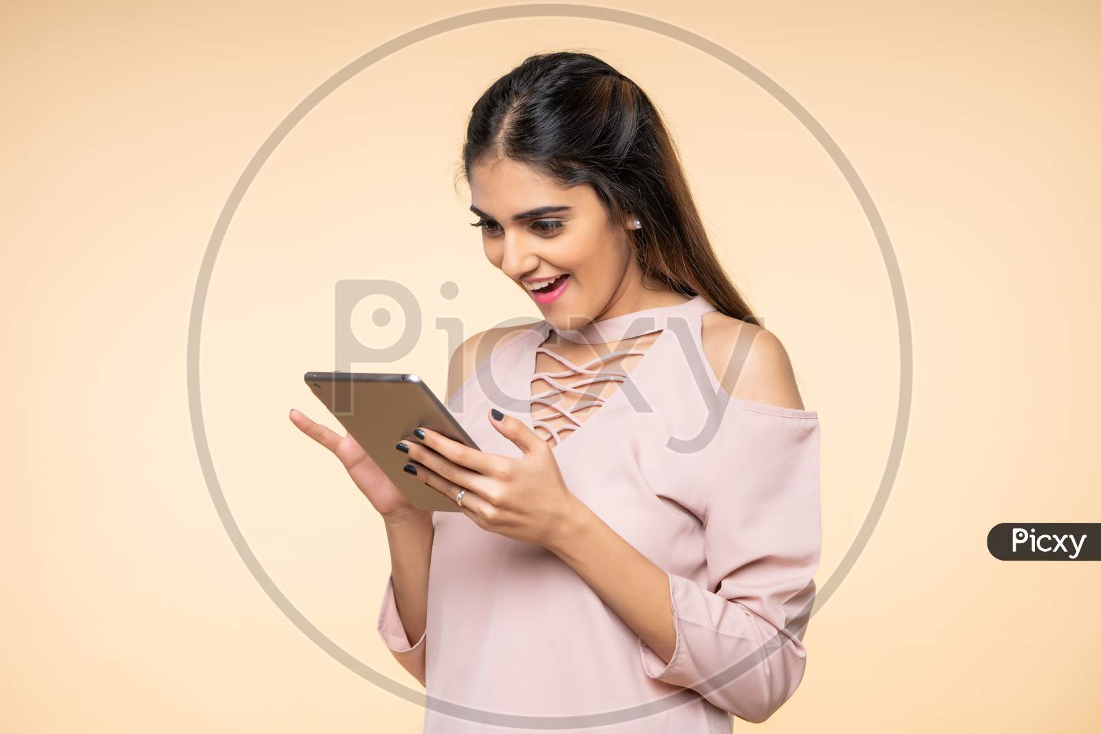 Indian excited young woman smiling while using Mobile Tab
