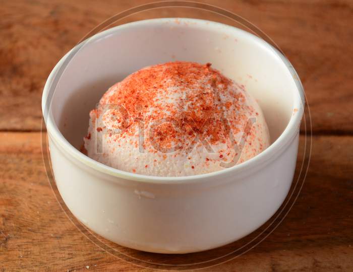 Chilli Peru Ice Cream Scoop Topped With Chilli Powder Served In A Bowl Over A Rustic Wooden Table, Selective Focus