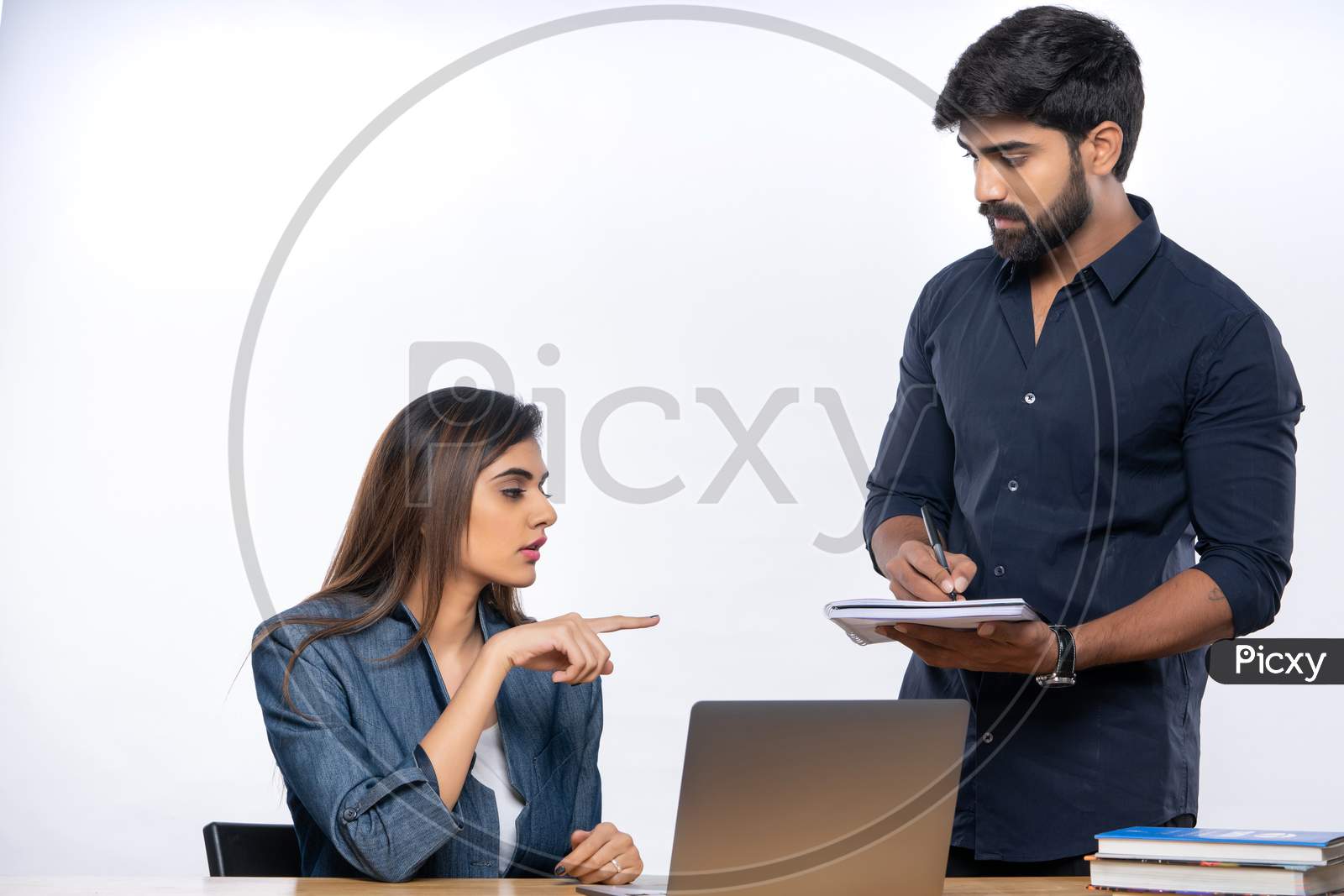 Indian female boss discussing office work with male employ
