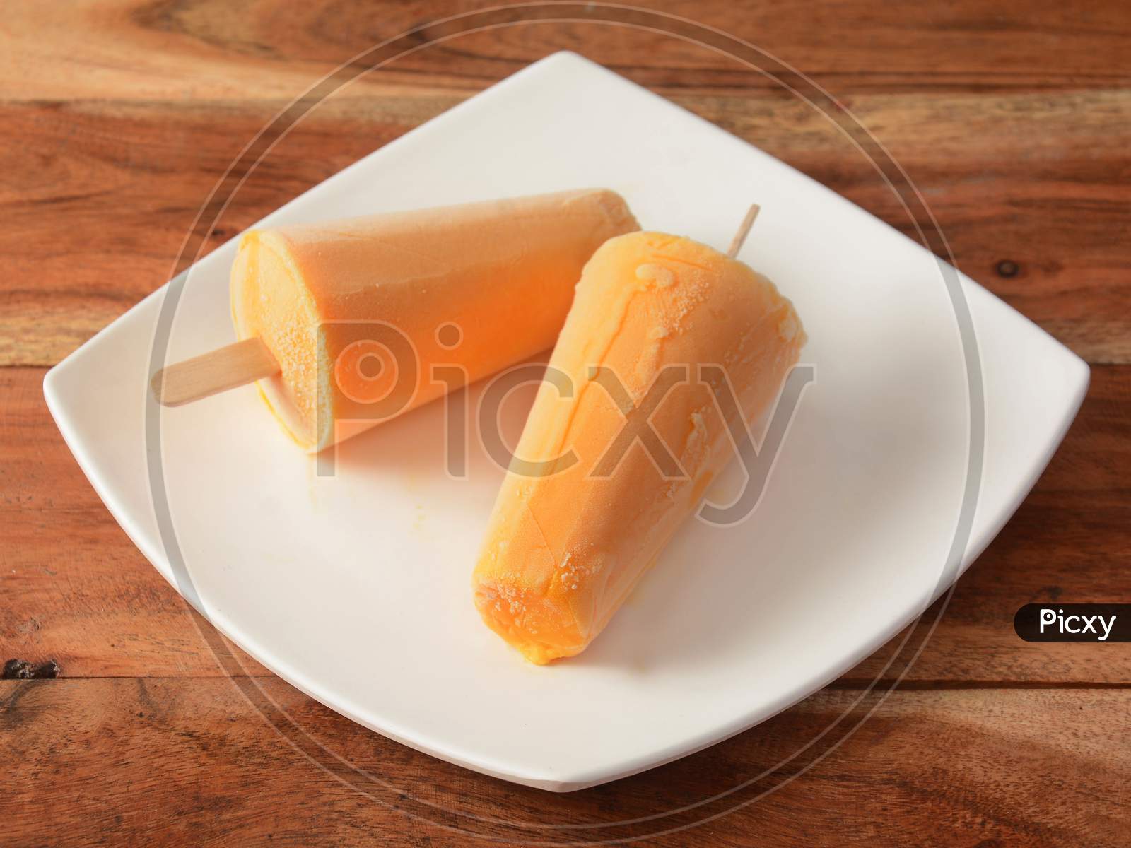 Kesar Kulfi Served In White Plate Over A Rustic Wooden Background, Selective Focus