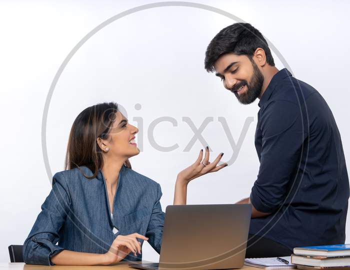 Indian male and female office colleagues smiling at each other