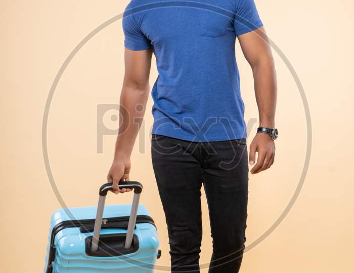 Indian smiling young traveler with a trolley bag
