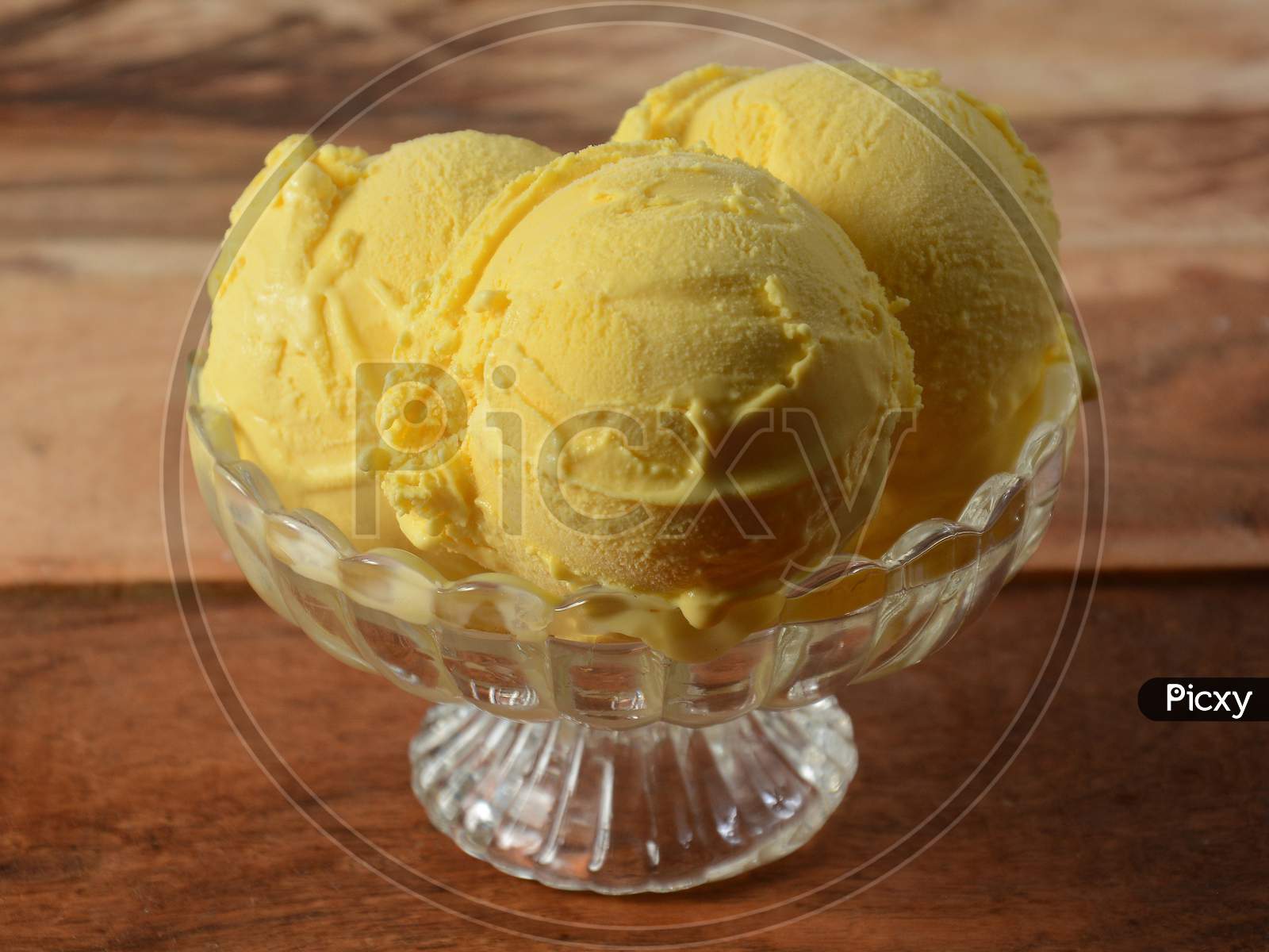 Mango Ice Cream Scoops Served In A Glass Bowl Over A Rustic Wooden Table, Selective Focus