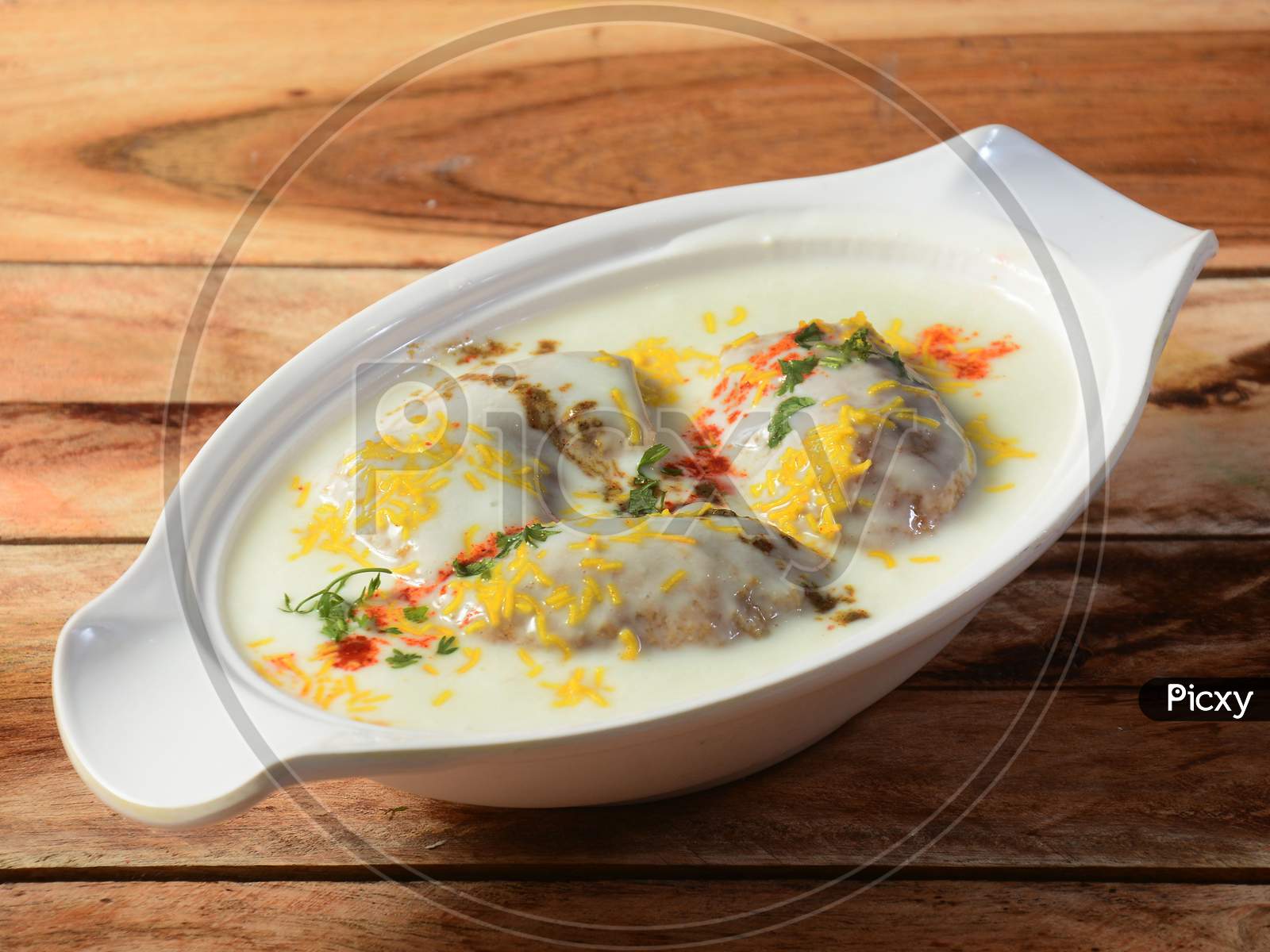 Dahi Vada Or Bhalla Is A Popular Snack In India. It Is Prepared By Soaking Vadas In Thick Dahi / Curd. Garnished With Coriander Leaves, Grated Carrots And Kara Boondi With Tamarind Chutney, Selective Focus