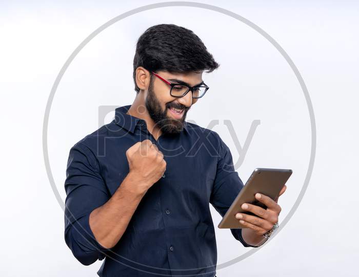 Indian man excited and gesturing success while using a tab