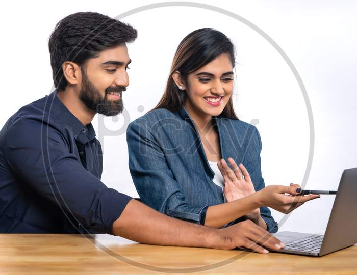 Indian office colleagues smiling while discussing work with a laptop