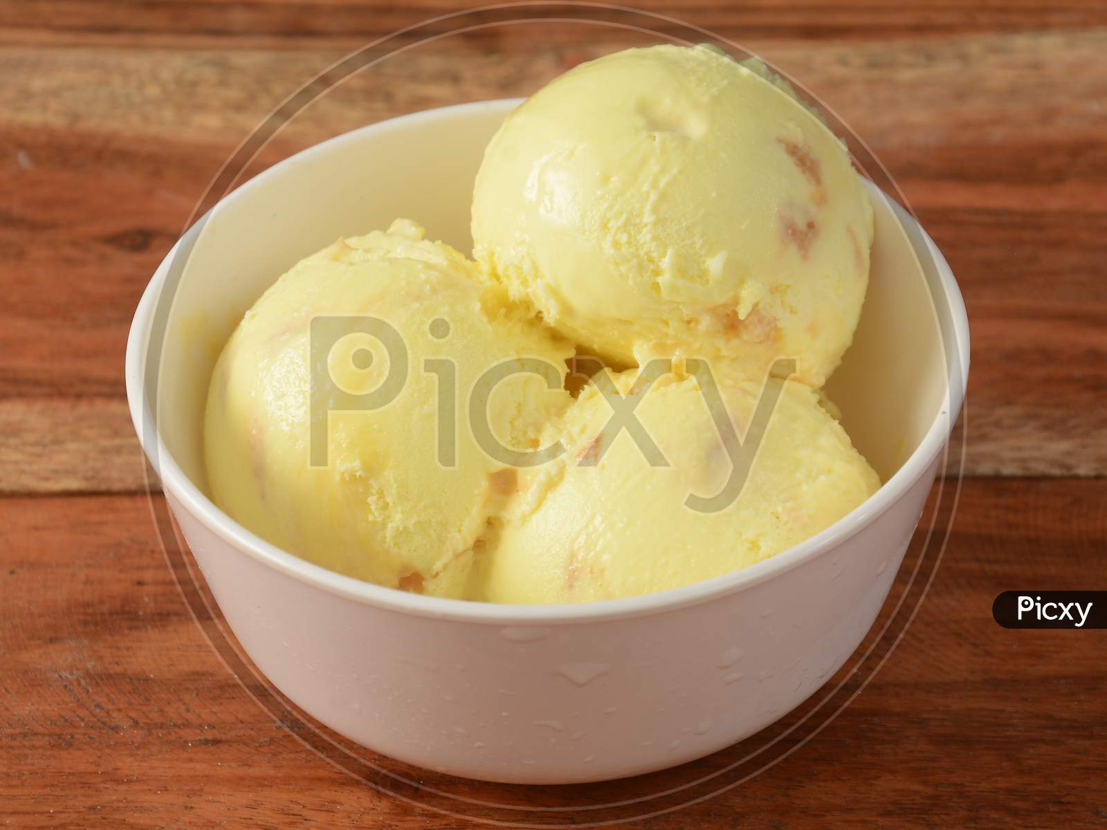 Butter Scotch Ice Cream Scoops Served In A Bowl Over A Rustic Wooden Table, Selective Focus