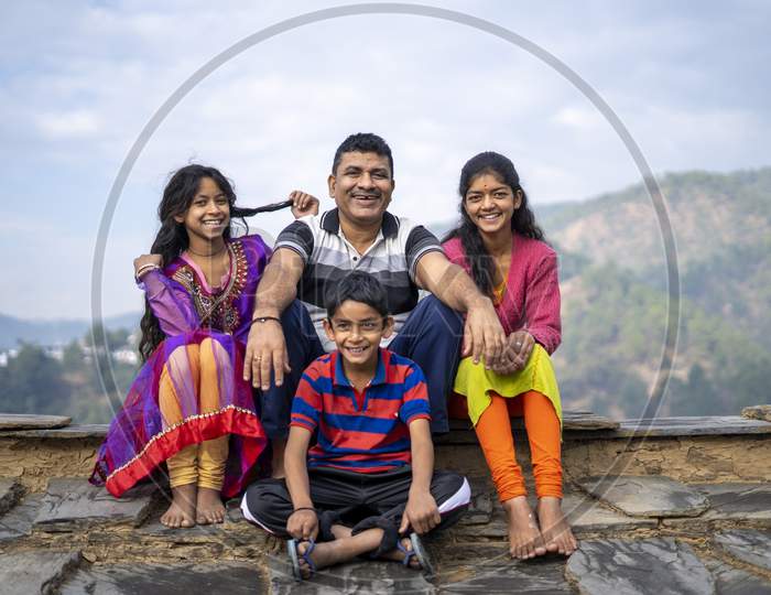 Indian Father Sitting With His Kids Smiling While Looking Into The Camera. Happy Family Concept.