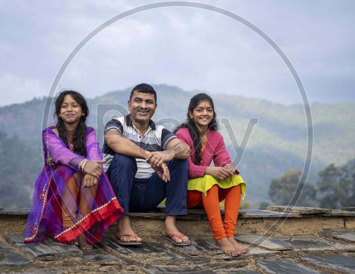 Indian Father Sitting With His Daughters And Smiling, Happy Family Concept.