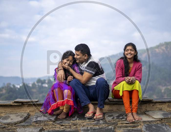 Indian Father Sitting With His Daughters And Smiling, Happy Family Concept.