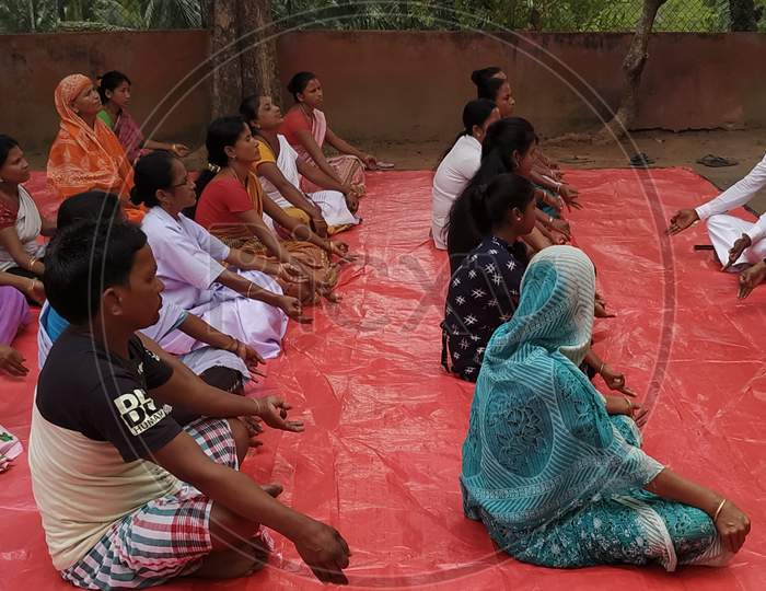 An instructor showing simple Yoga poses to people from different sections of community