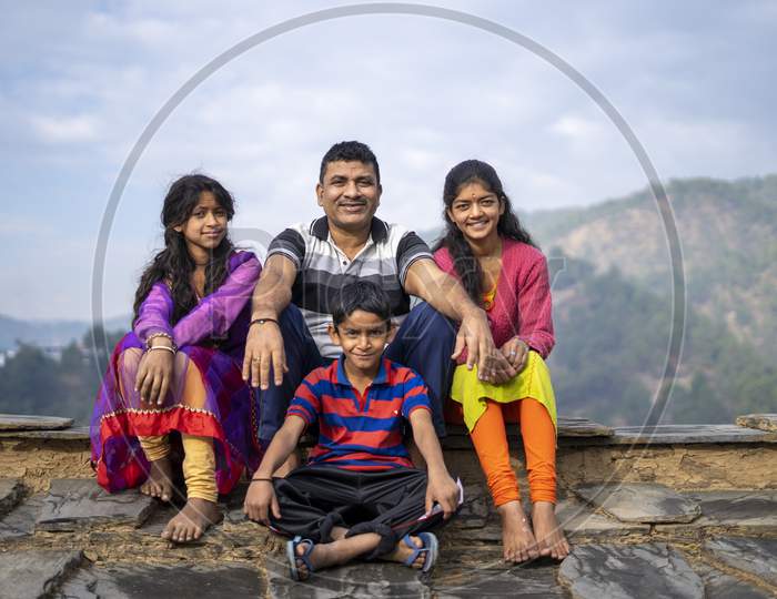 Indian Father Sitting With His Kids Smiling While Looking Into The Camera. Happy Family Concept.