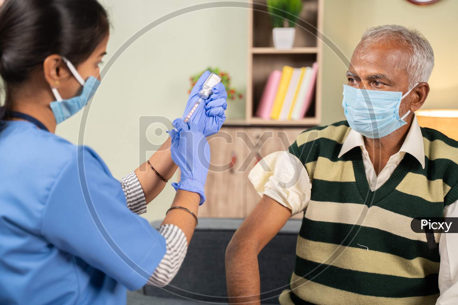 Doctor Preparing Vaccination Shot To Elderly Patient By Holding Syringe At Home - Concept Of Home Health Check To Seniors During Coronavirus Covid-19 Pandemic.