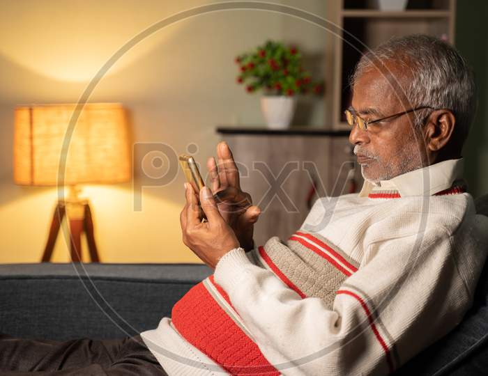 Old Man Busy Using Mobile Phone At Home While Sleeping On Sofa - Concept Of Senior People Using Technology, Internet And Social Media.