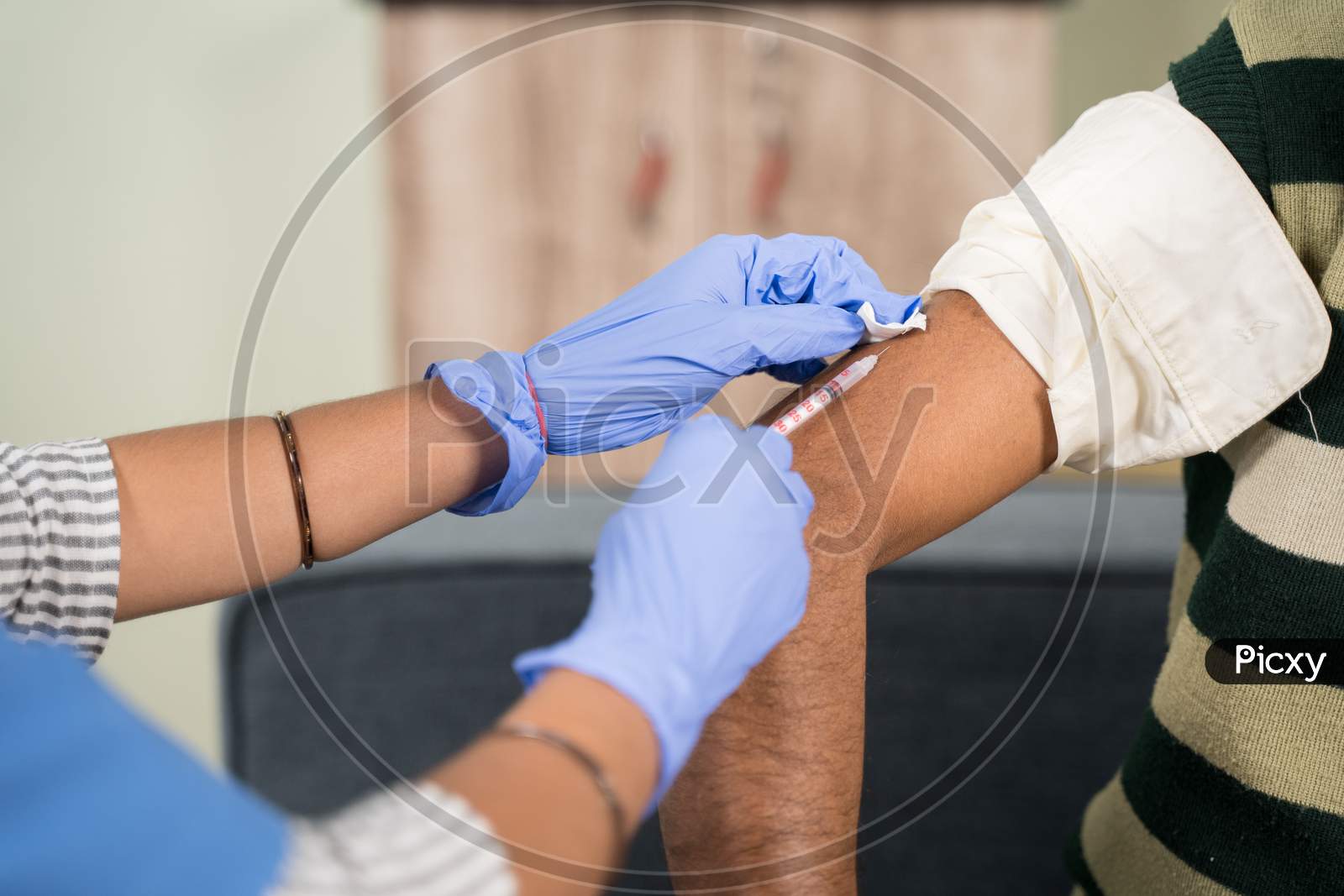 Close Up Of A Doctor Making A Vaccination Shot In The Shoulder Of Patient At Home - Concept Of Home Health Check.
