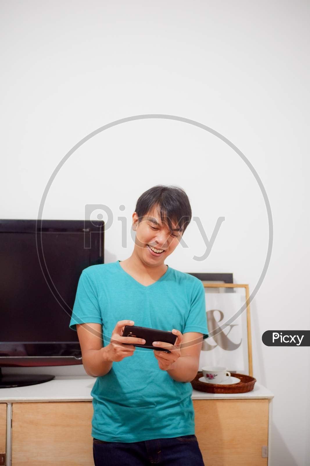 Asian Boy Enjoys Playing Video Games On His Mobile Phone