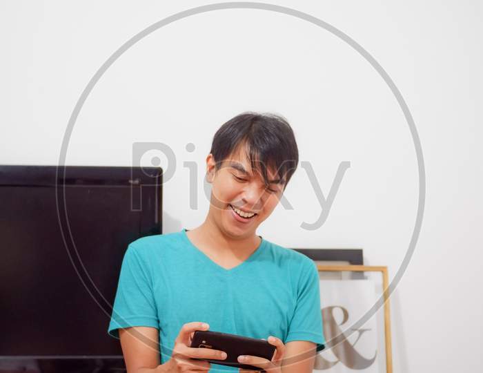 Asian Boy Enjoys Playing Video Games On His Mobile Phone