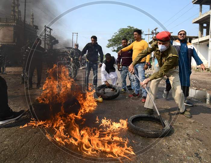 Police remove  burning tyres during a protest    in support of the nationwide strike called by agitating farmers against Centre's farm reform laws, in Nagaon District of Assam , Tuesday, Dec. 8, 2020.