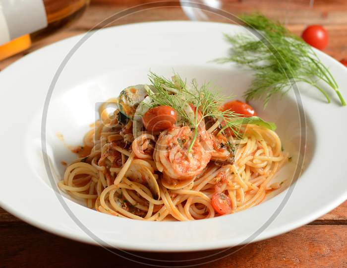 Italian Seafood Pasta Pescatore Served In A White Plate On A Rustic Wooden Table, Selective Focus