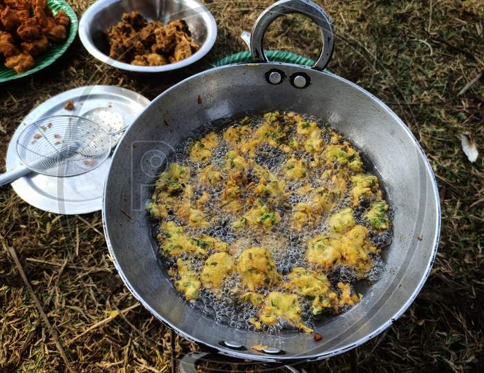 Onion (payaz) pakoda being fried in oil on picnic spot.