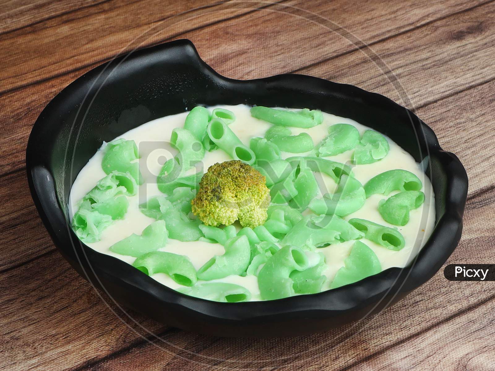 Green Lantern Pasta Topped With A White Creamy Sauce And Basil Served In A Plate On A Rustic Wooden Table, Selective Focus