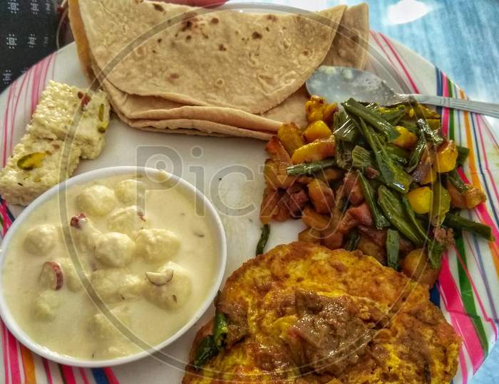 Roti, Omlet, Mix Veg And Rasmalai In A White Plate