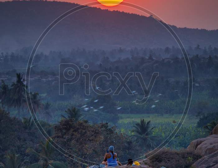 Tourist Couple or Hippes  Enjoying Sunset  From Anjanadri Hill Top in Hampi