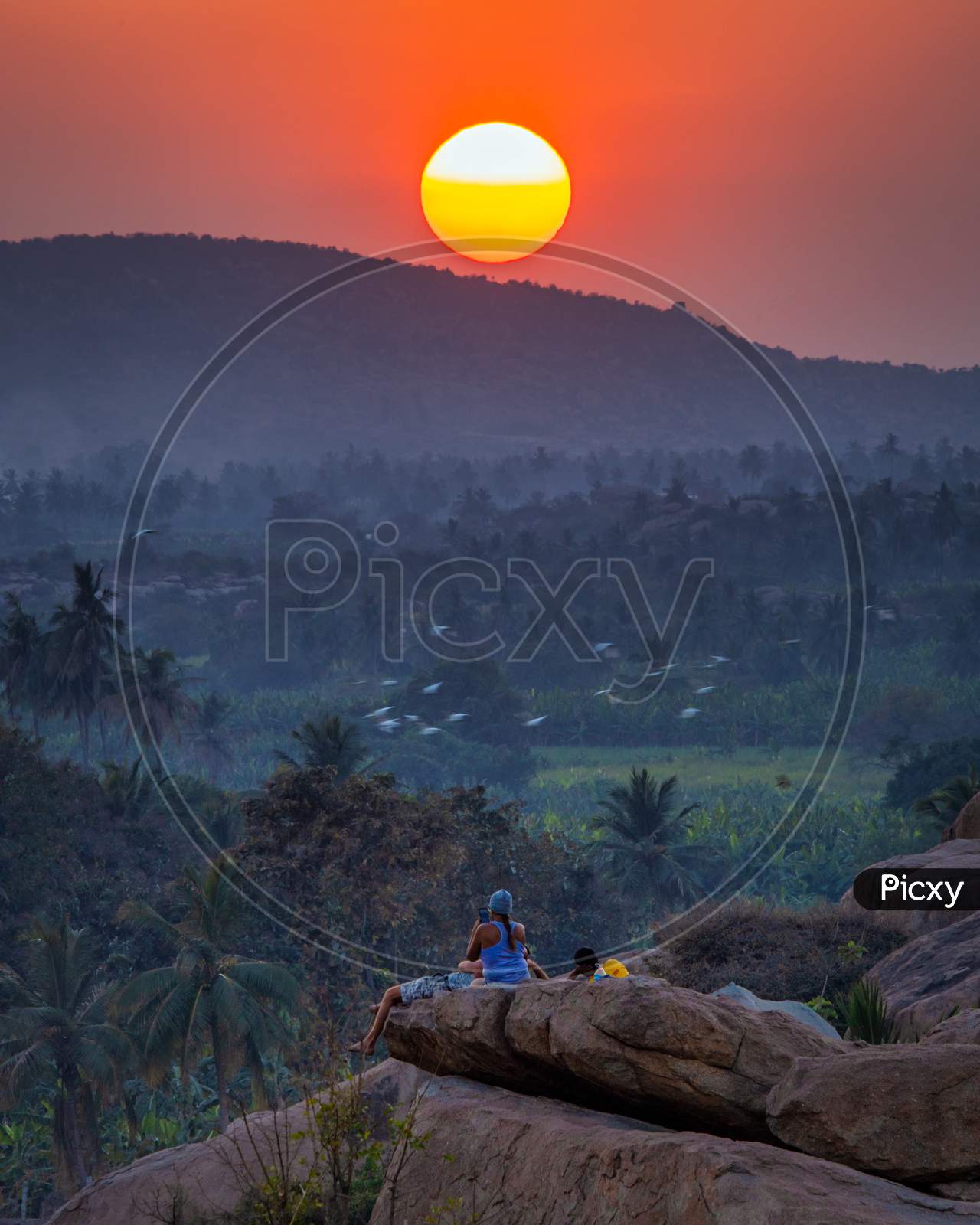 Tourist Couple or Hippes  Enjoying Sunset  From Anjanadri Hill Top in Hampi