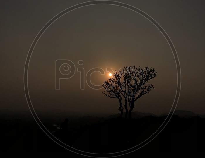 Reflection Of Dried Tree on Pond Water Over a Sunset Sun  at Anjanadri Hill Top, Hampi
