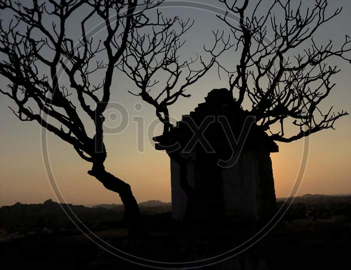 Silhouette Of  Temple And Dried Tree on Hemakuta Hill Top , Hampi