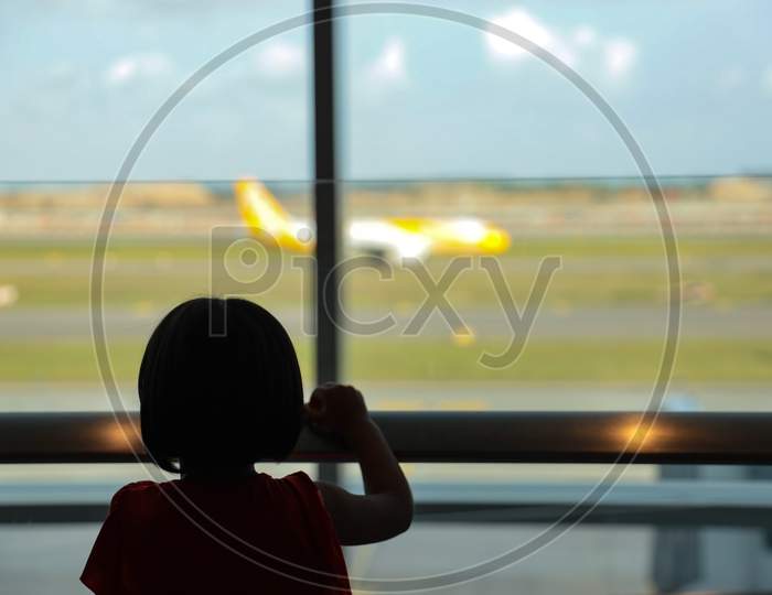 A Girl Child Looking Through A Window Shield at airport 