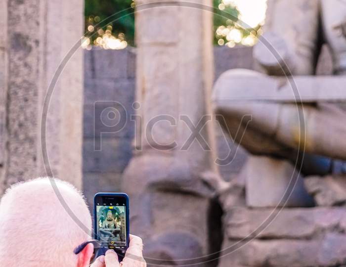 A Foreigner taking a picture of statue with his phone
