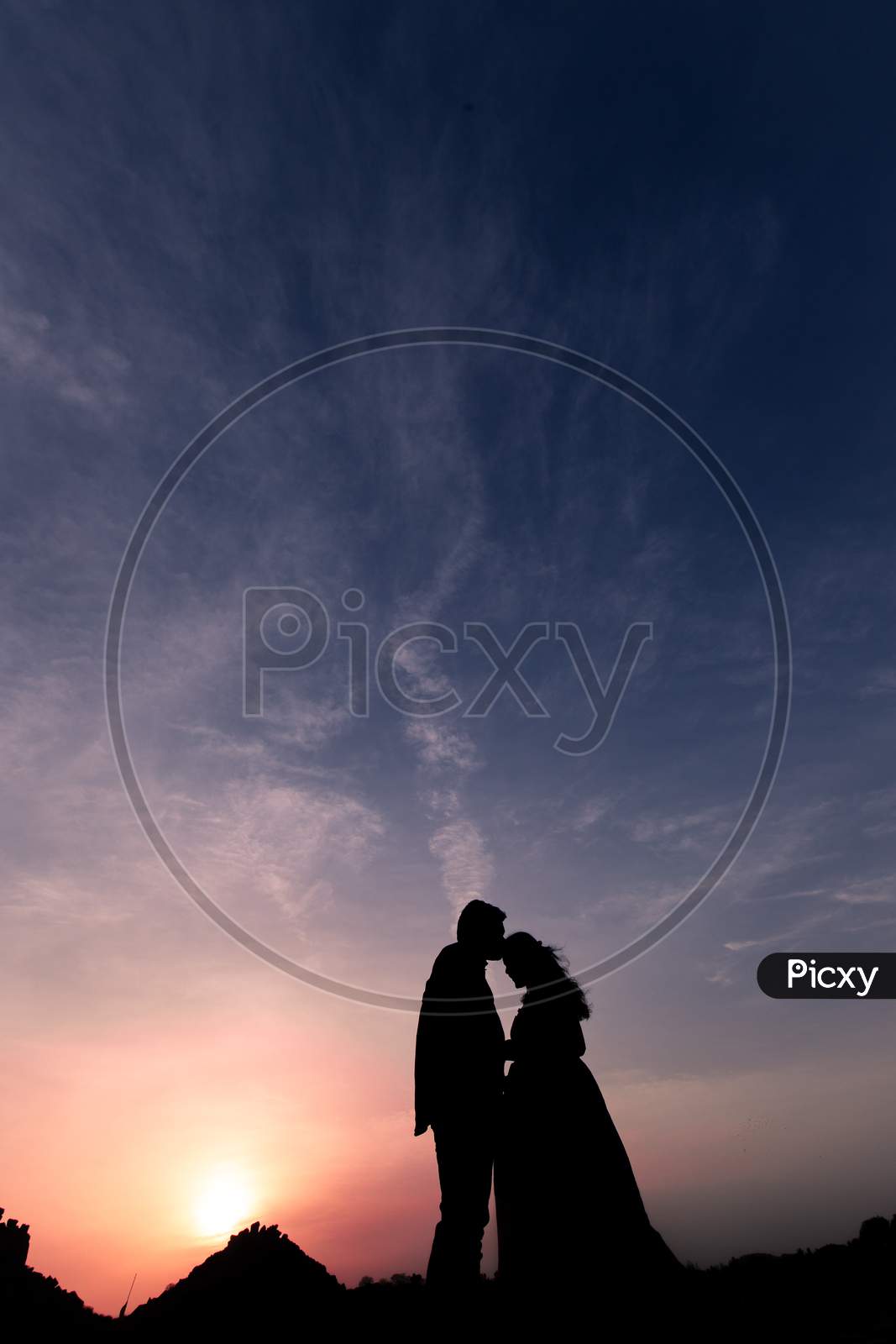 Silhouette of Indian man kissing a woman during sunset