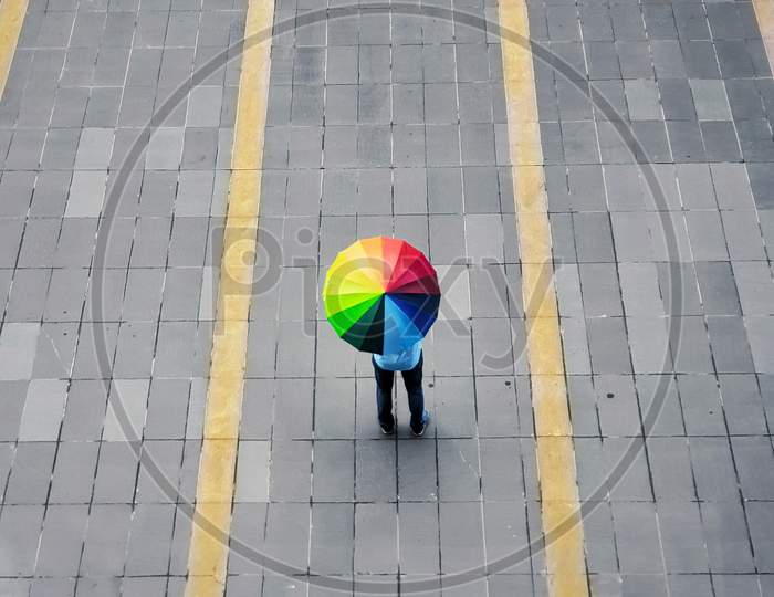 Indian Man standing holding a colorful umbrella