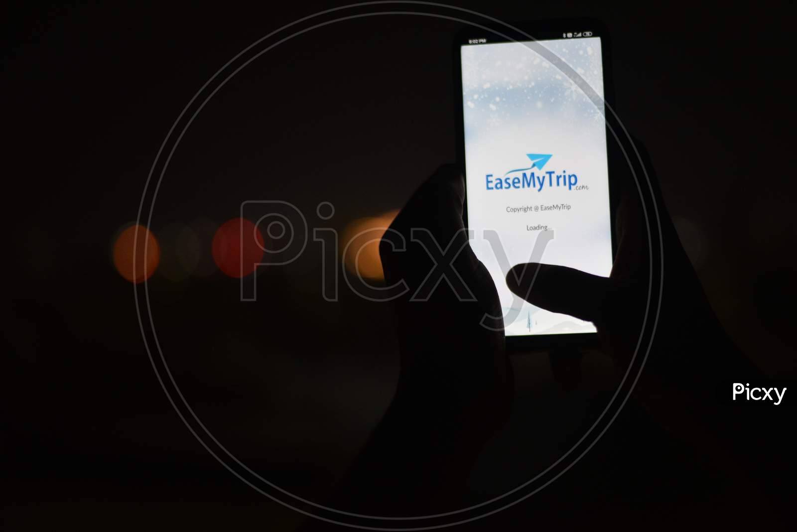 Indian man using Android EaseMyTrip.Com app in the dark