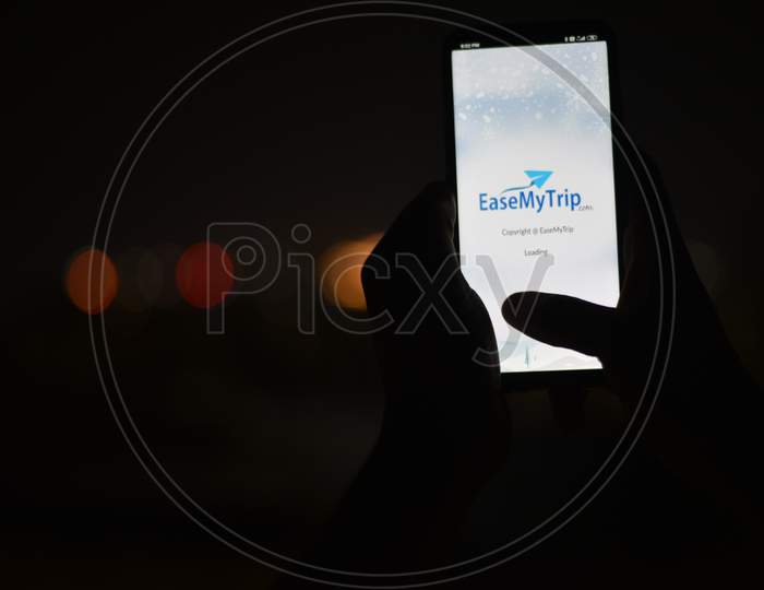 Indian man using Android EaseMyTrip.Com app in the dark