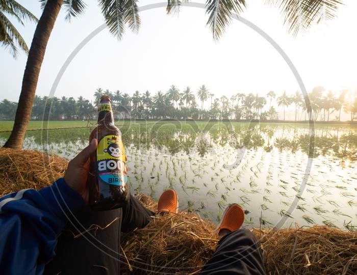 Indian Man holding Bira Beer during sunrise